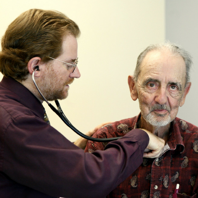 doctor checking heart of a senior man